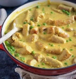 The best easy curried sausages with sliced carrots and peas in a rich curry gravy served in a skillet.