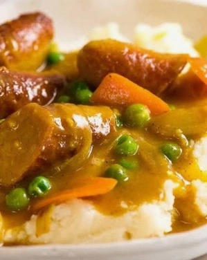 The best easy curried sausages with sliced carrots and peas in a rich curry gravy served in a skillet.