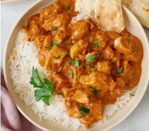 The best easy butter chicken with creamy orange tomato sauce served in a copper bowl with basmati rice.