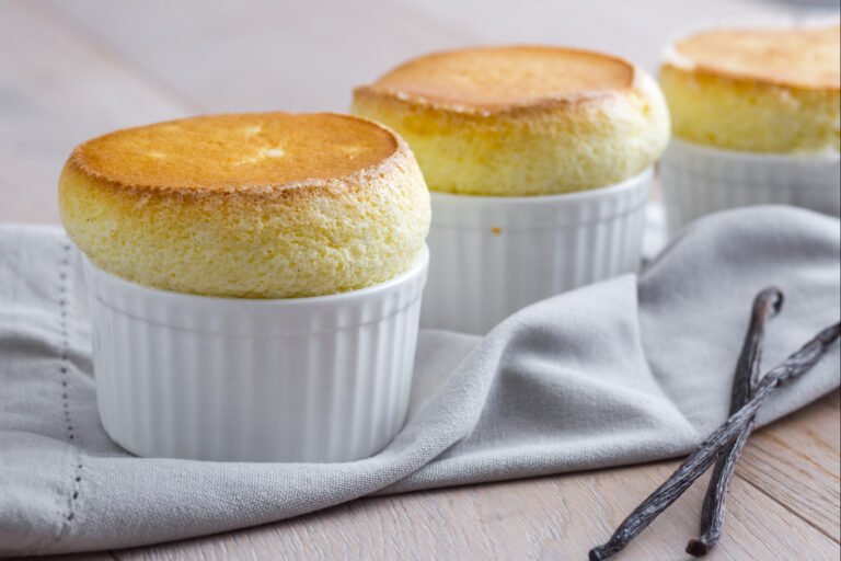The best easy vanilla soufflé baked to a golden brown and perfectly puffed up in a white ramekin.