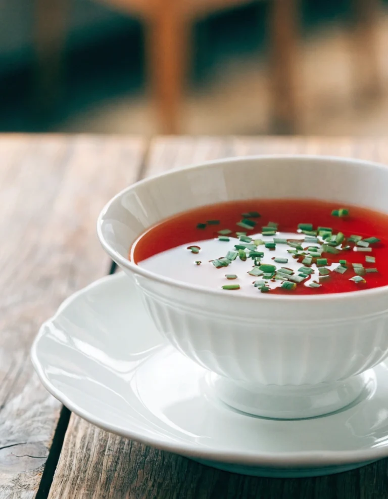 Sherry Tomato Consommé served in an elegant soup cup garnished with fresh chives